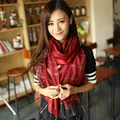 Women's silk plaid scarf with gold metallic threads shown on model in cozy indoor setting - Red