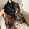Close-up of orange floral embroidery on translucent black silk and wool shawl fabric - Elegant Black