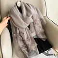 Close-up of embroidered silk wool shawl with 3D lavender floral patterns and camellia brooch - Gray