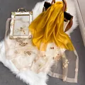 Détail d'une écharpe en soie avec broderie florale et organza sur tapis en fausse fourrure - 195CM / Jaune