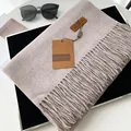 Beige faux cashmere fringe scarf with leather logo label in luxury setting - Extended Version / Shrimp Color