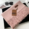 Pink cashmere-feel tassel scarf with leather brand tag on a stylish display setup - Extended Version / Heathered Pink