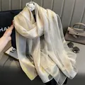 Détail d'une écharpe en soie avec rayures dorées et texture de tissu beige léger - 195CM / Beige
