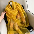 Vue détaillée des broderies florales et paillettes sur le châle en laine de soie jaune - Jaune / 195CM