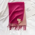Detalle de una bufanda reversible de estilo cachemira con flecos y etiqueta de marca - Rosa Roja