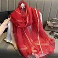 Gros plan d'une écharpe en soie rouge à rayures dorées drapée sur un mannequin - 195CM / Rouge
