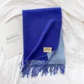 Detailed close-up of double-sided blue cashmere-like scarf with fringe and brand label - Sapphire Blue