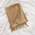 Close-up of camel cashmere scarf with decorative tassels and vintage woven brand label - Beige