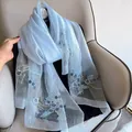 Detailed embroidery of light blue flowers on sheer silk wool scarf draped over a chair - 195CM / Blue