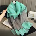 Détail d'un foulard en soie vert menthe à rayures grises avec accessoire camélia blanc - Vert