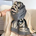 Detailed view of thick zebra-striped scarf with tassel edges on a warm beige knitwear - Gradient Zebra-Gray