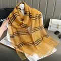 Detail of golden plaid silk scarf texture with soft fringe edges and classic check pattern - Yellow