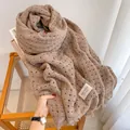 Detail of tan hollow knit wool scarf showing thick texture and tassel fringe on a wooden table - 190cm / Hollow - Light Coffee