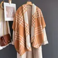 Orange and beige plaid cashmere-feel shawl draped over a beige coat on a wooden hanger - Beige