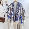 Detail of bohemian geometric jacquard knit shawl with fringes over a wool coat - Blue