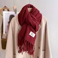 Detail of dark red knitted scarf with tassels and brand label on a coat - Angola Red