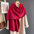 Detail of red plaid cashmere-like scarf draped over a beige coat with a chain bag - Red