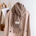 Close-up of thick dark coffee scarf with fringe detail and label on a wool coat - Flax Khaki