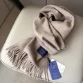 Bufanda clásica de lana color avena con flecos en una silla minimalista - Color Té con Leche