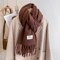 Detail shot of coffee brown tassel scarf showing soft fringe texture and woven brand label - Reddish Brown