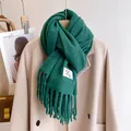 Detail of dark green thick scarf with tassels on wooden hanger and beige coat - Dark Green