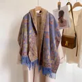Detail view of ethnic floral scarf with blue fringe styled on a beige winter coat - Maya Pattern Blue