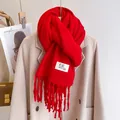 Solid red knitted scarf with tassels and label detail paired with a beige coat - Red