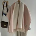 Detailed macro view of wool blend scarf tassels and stitched label on winter shawl - Pink White