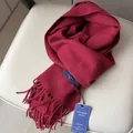 Bufanda de lana color burdeos con flecos y elegante etiqueta azul sobre asiento de piel crema - Rojo Angola