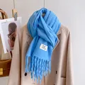 Vibrant blue knitted scarf with long tassels and logo tag on beige coat - Azure Blue