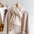Minimalist beige knitted scarf with tassels and woven label on matching wool coat - Beige