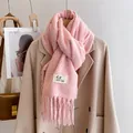 Pink knitted winter scarf with long tassels and woven label on beige wool coat - Peach Blossom