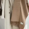 Brown wool blend long scarf with fringe detail paired with a cream-colored coat - Camel