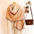 Detail of warm orange paisley cashmere feel scarf draped over a beige wool coat - 185 / Orange And Beige