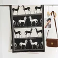 Elegant black and white horse pattern cashmere shawl with fringed edges hanging on a rack - Black and White