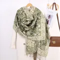 Detail of green paisley jacquard shawl with fringe on coat and vintage bag - Army Green
