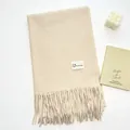 Dettaglio di sciarpa beige effetto cashmere con frange e etichetta minimalista - Beige