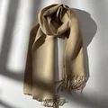 Close-up of premium wool scarf with fringe detail and elegant window light shadows - Beige