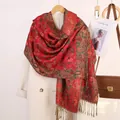 Sciarpa con motivo paisley rosso e verde con nappe appesa su un cappotto di lana - Rosso