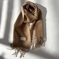 Detail of wool muffler with fine texture, long tassels, and cozy woven fabric tag - Light Camel