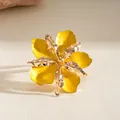 Elegant gold pleated flower ring with yellow enamel petals in a warm lighting setup. - Ring / Yellow