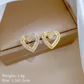 Detailopname van gouden hartvormige oorbellen met zirkoon, maat 1,5x1,5cm - Zilveren Pin + Koperen Basis / Hart Baguette Zirkoon Oorbellen