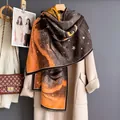 Luxury owl print faux cashmere scarf with tassels styled on a white coat and coat hanger - 185cm / Orange