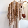 Detail of hooded cape with geometric rhombus pattern and decorative fringe trim - Camel