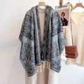 Detail of grey and white plaid scarf with fringe, draped on coat in a cozy setting - Black