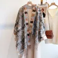 Detailed shot of ethnic paisley cashmere-feel scarf with long tassels on beige wool coat - Gray