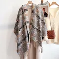Detail of grey paisley floral scarf with fringe trim paired with a stylish beige coat - Gray