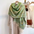 Dettaglio dello scialle jacquard geometrico verde e giallo con morbide frange bianche - Verde