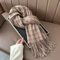 Classic brown plaid cashmere scarf with long tassels displayed on a leather background - Khaki