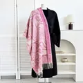 Detail of pink paisley cashmere-like scarf draped over a black winter wool coat - Bright Rose Red Paisley